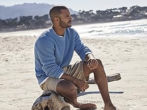 Man on beach sitting on drift wood