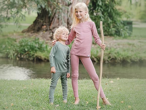 Siblings wearing Woolino Kids'' Merino Wool Thermal Tops & Leggings in Sage green and Blush pink.