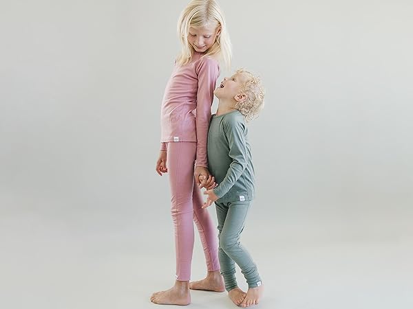 Siblings wearing Woolino Kids'' Merino Wool Thermal Tops & Leggings in Sage green and Blush pink.