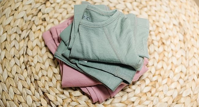 Folded pile of Woolino Kids'' Merino Wool Thermal Tops & Leggings in Sage green and Blush pink.