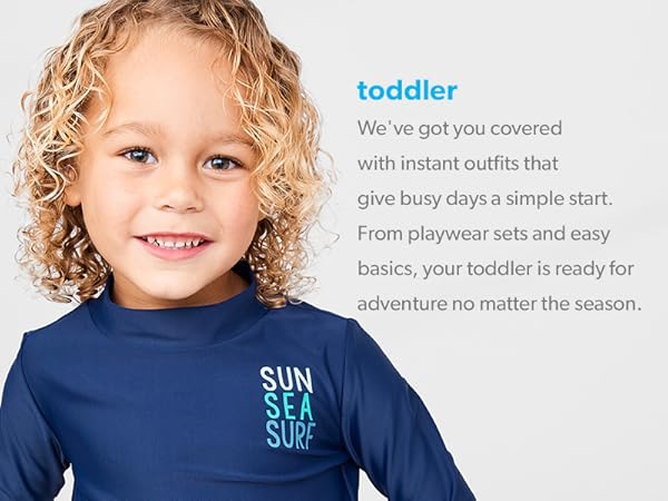 a toddler boy with blond curly hair in a navy swimsuit